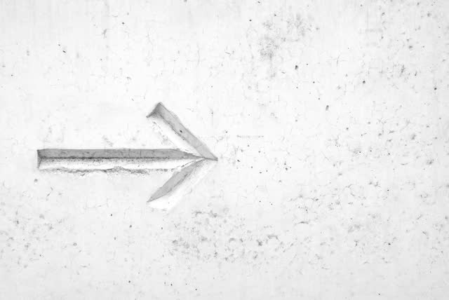 An arrow pointing right, pressed into pale concrete